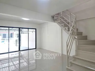 Spacious modern interior with sleek staircase and large windows, perfect for natural light lovers.