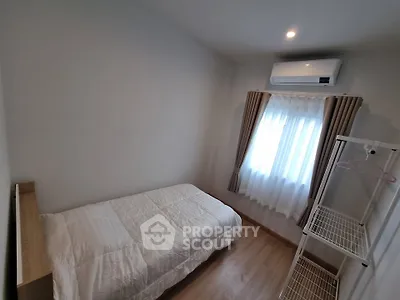 Cozy bedroom with single bed, air conditioning, and natural light from window.