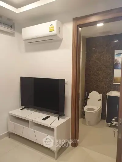 Modern living room with TV and air conditioning adjacent to a stylish bathroom.