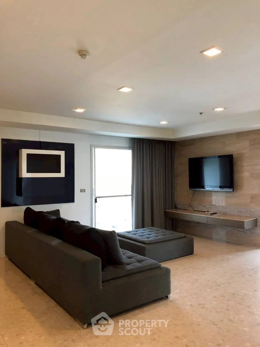 Spacious modern living room with sleek furniture and wall-mounted TV, perfect for relaxation and entertainment.