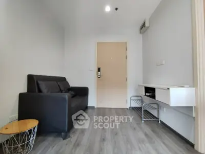 Modern minimalist living room with sleek black sofa and stylish wooden flooring.
