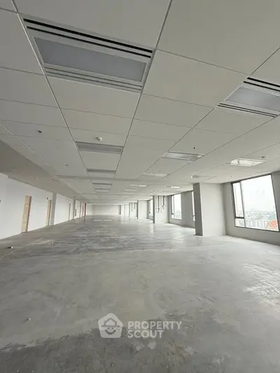 Spacious open-plan commercial office space with large windows and modern ceiling design.