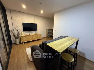 Modern living room with stylish furniture and wooden flooring, featuring a sleek TV setup and cozy seating area.
