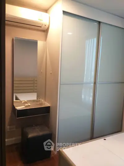 Modern bedroom with sleek sliding closet doors and compact vanity area.