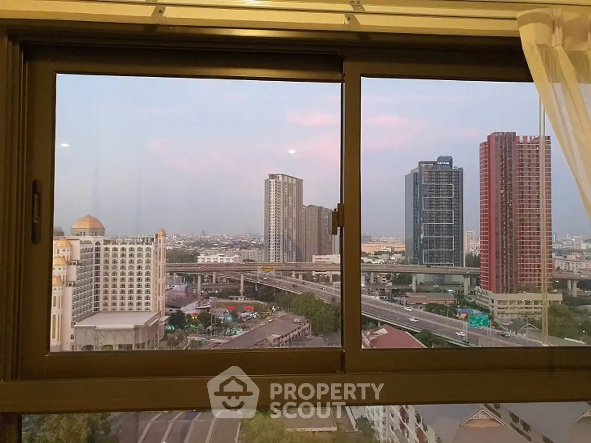 Stunning cityscape view from a high-rise apartment window at sunset.