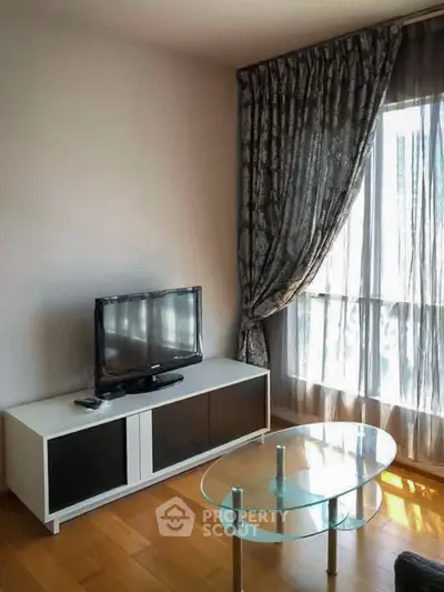 Cozy living room with TV and elegant curtains, perfect for relaxation.