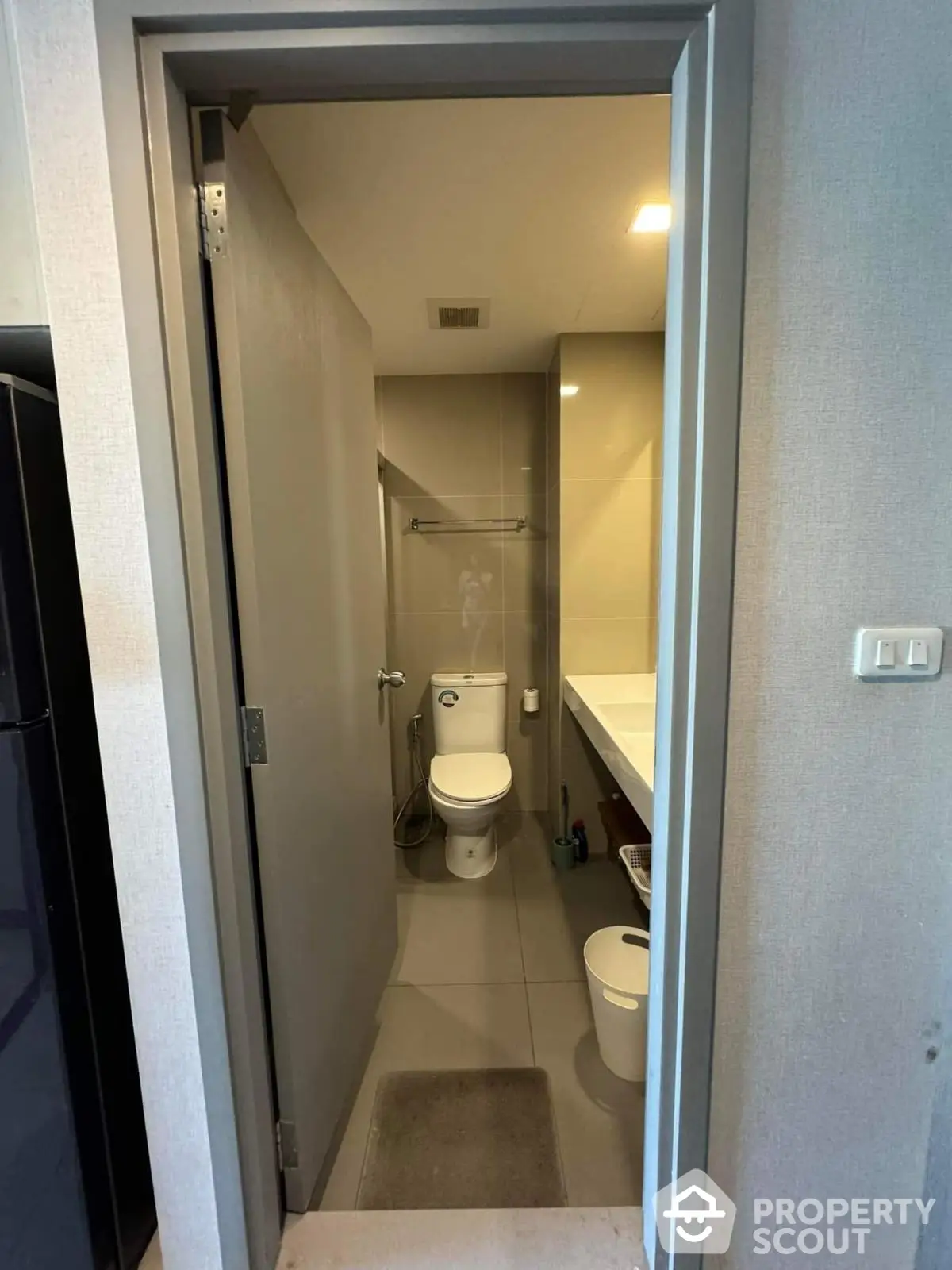 Modern bathroom with sleek design and neutral tones, featuring a toilet and vanity area.