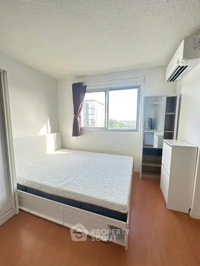 Bright bedroom with large window, air conditioning, and modern furnishings in a cozy apartment.