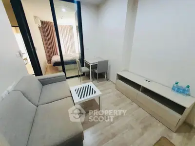 Modern living room with sleek furniture and view into a cozy bedroom