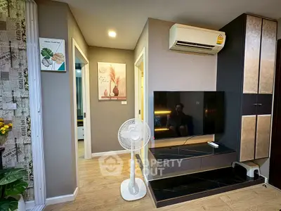 Modern living room with sleek TV setup and air conditioning, featuring stylish decor and wooden flooring.