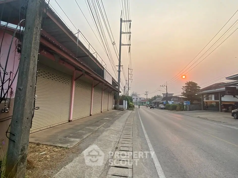 Quiet suburban street with closed shops and sunset view, ideal for commercial real estate opportunities.