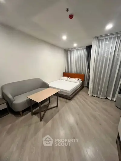Modern studio apartment with cozy bed and stylish sofa in a minimalist design.