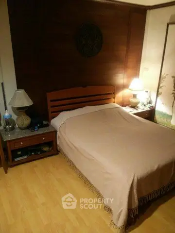 Cozy bedroom with wooden headboard and warm lighting, perfect for relaxation.