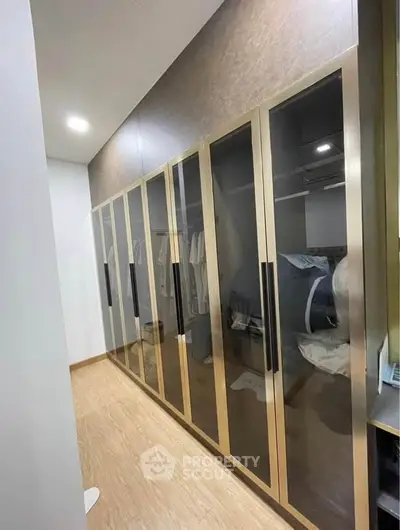Luxurious walk-in closet with sleek glass doors and ample storage space