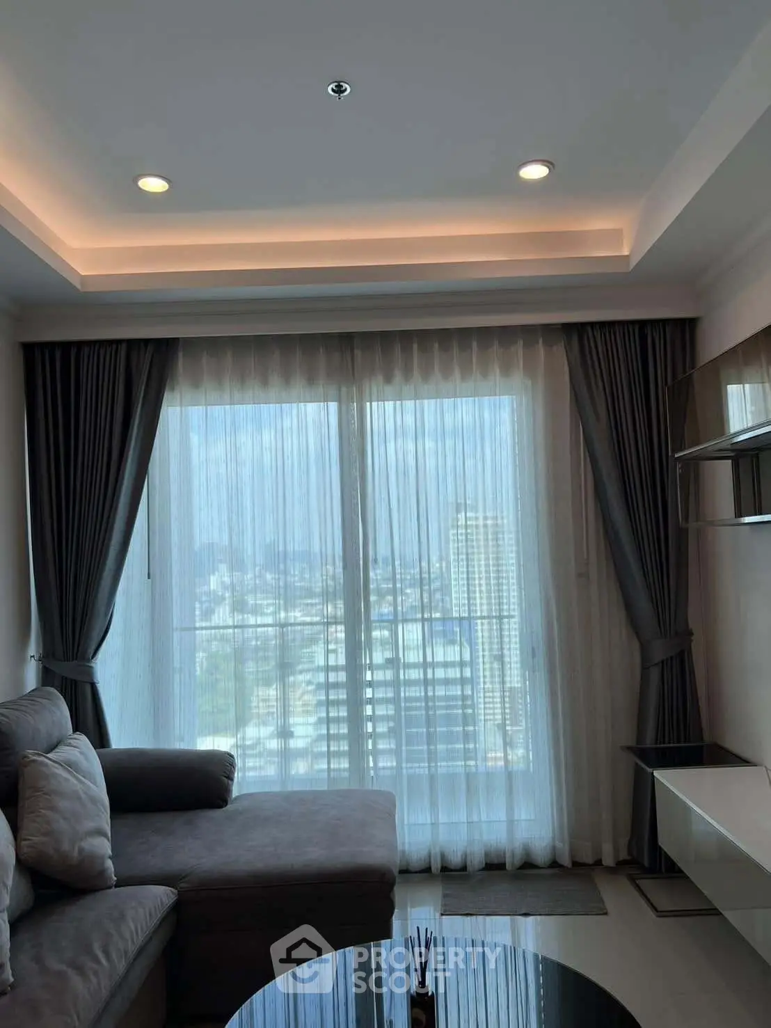 Modern living room with large windows offering stunning city views and elegant decor.