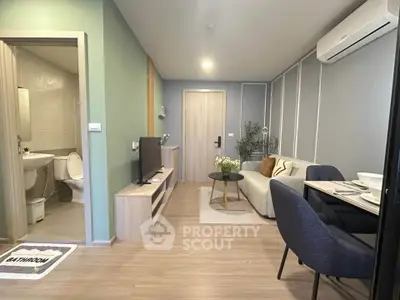 Modern living room with stylish decor and open layout, featuring a cozy seating area and adjacent bathroom.