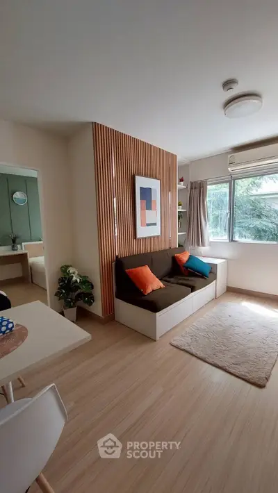 Modern living room with stylish decor and natural light, featuring a cozy sofa and wooden accents.