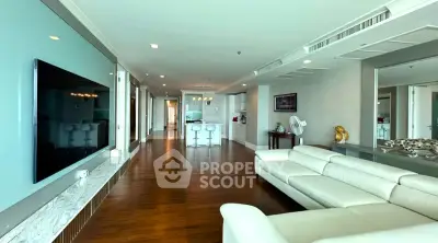 Spacious modern living room with sleek design and open layout, featuring a large TV and elegant white sofa.
