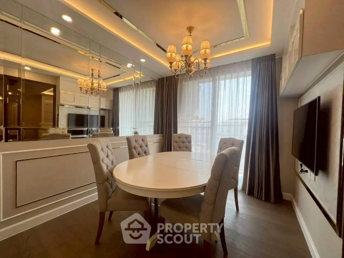 Elegant dining area with round table, plush chairs, and chandelier lighting in a modern apartment.
