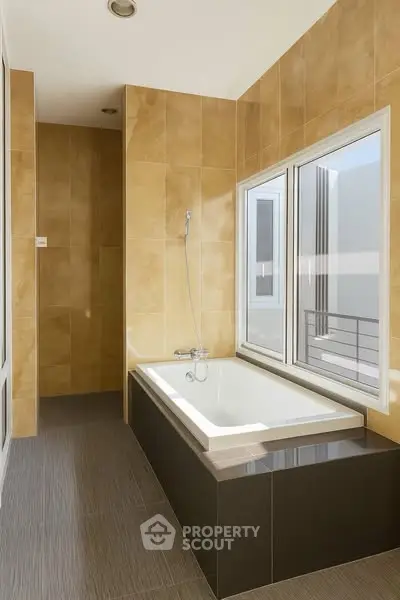 Modern bathroom with large window and built-in bathtub in luxury apartment.