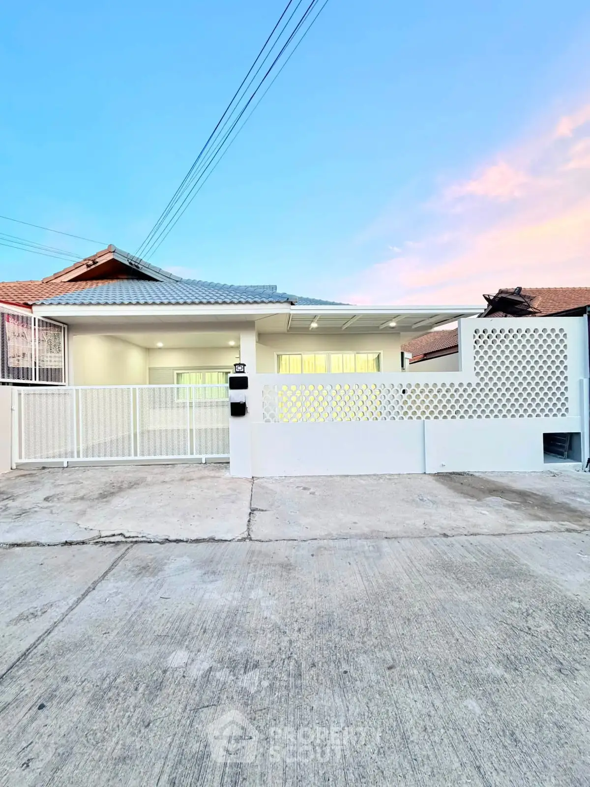 Charming single-story home with modern facade and spacious driveway at sunset.