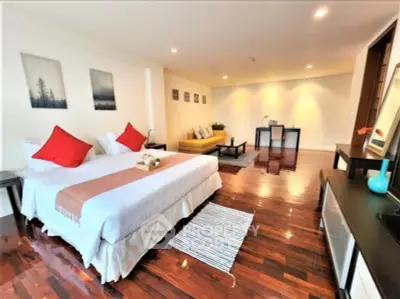 Spacious bedroom with elegant decor and hardwood floors in modern apartment.