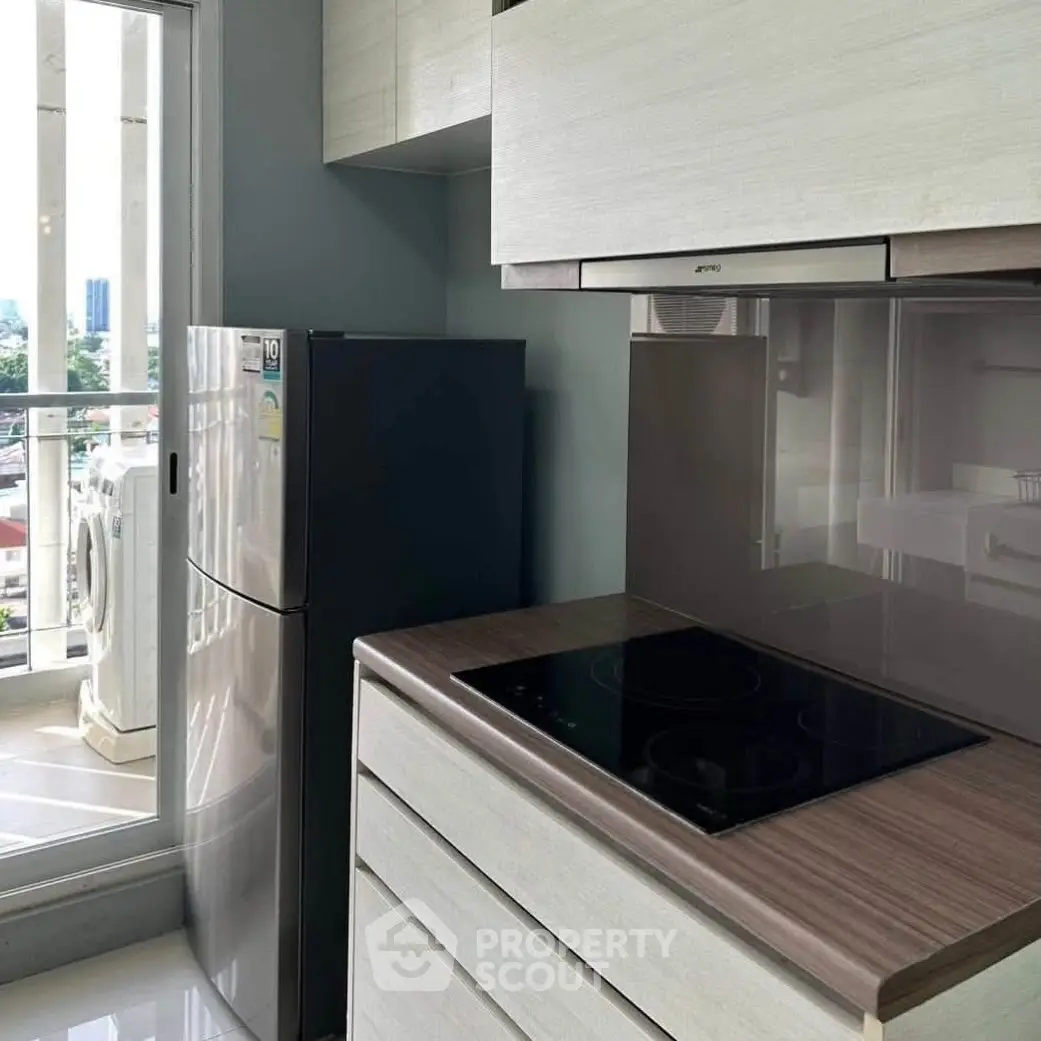 Modern kitchen with sleek appliances and balcony view in urban apartment