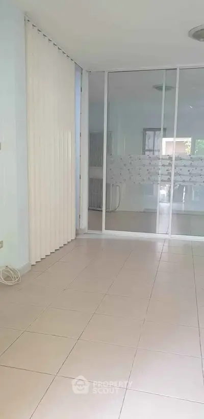 Spacious empty room with tiled flooring and sliding glass doors