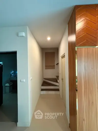 Modern hallway with wooden accents and staircase leading to upper floor