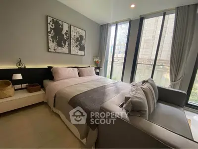 Modern bedroom with large windows and stylish decor in urban apartment.