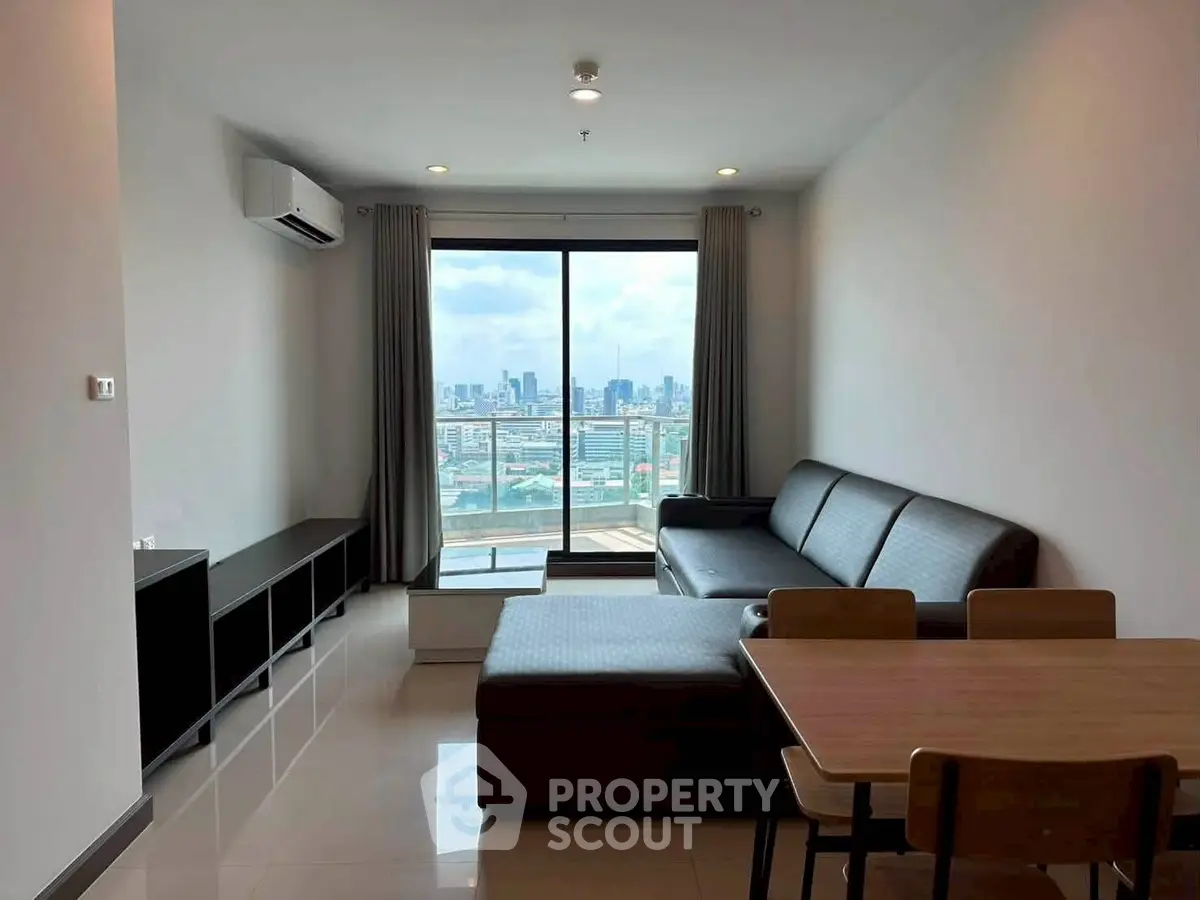 Modern living room with city view, featuring sleek furniture and large windows for natural light.