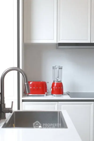 Modern kitchen with sleek white cabinets and stylish red appliances.
