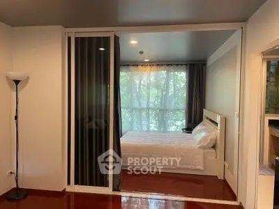 Modern bedroom with large window and sleek design, featuring a cozy bed and stylish floor lamp.