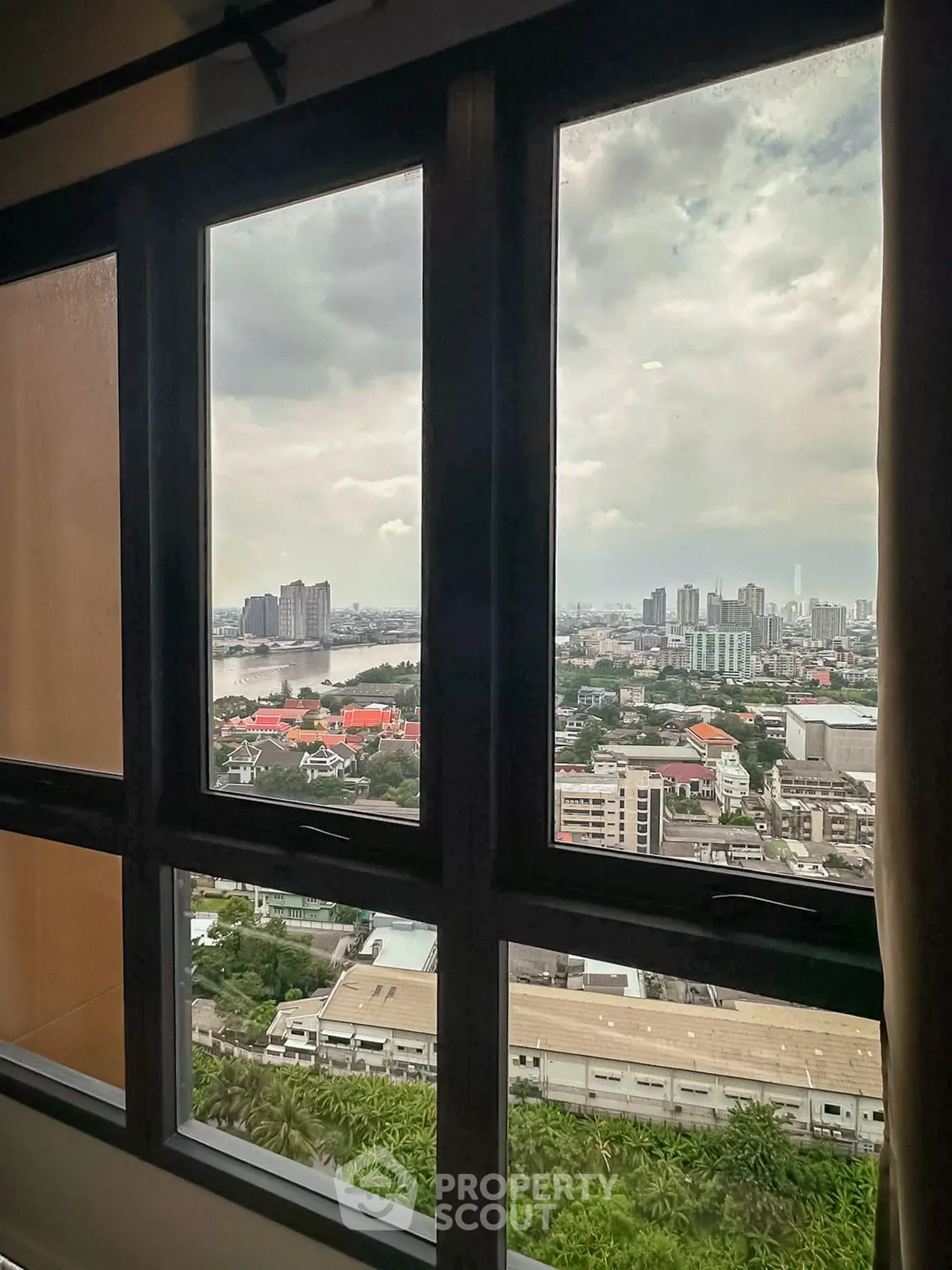 Stunning cityscape view from high-rise apartment window, showcasing urban skyline and river.