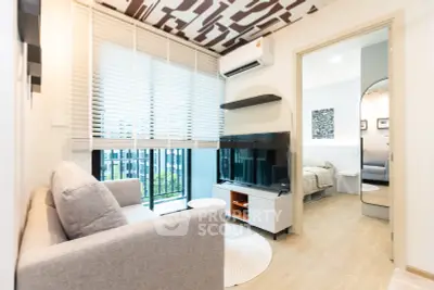 Modern living room with stylish decor and natural light, featuring a cozy sofa and sleek TV setup.