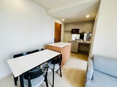 Modern open-layout kitchen and dining area with sleek furniture and bright lighting.