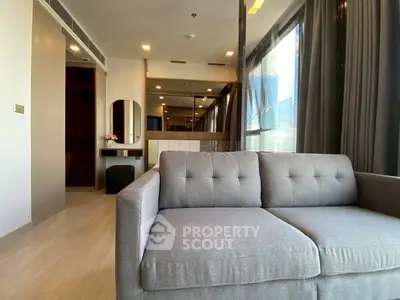 Modern living room with stylish gray sofa and large windows for natural light.