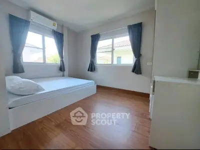 Spacious bedroom with wooden flooring and large windows in a modern home.