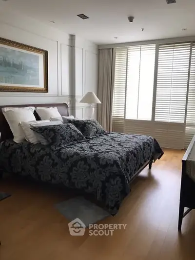 Elegant bedroom with large window and stylish decor in modern apartment.