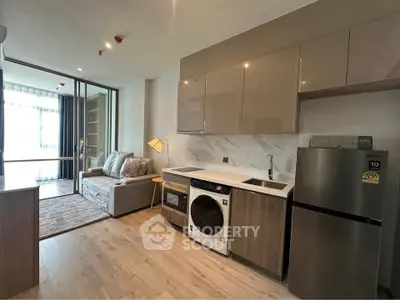 Modern open-layout living room with kitchen featuring washing machine and fridge, stylish cabinetry, and cozy seating area.
