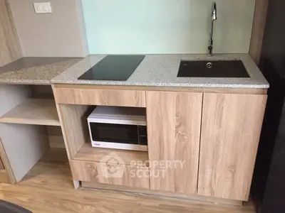 Modern compact kitchen with sleek design featuring built-in microwave and electric stove.