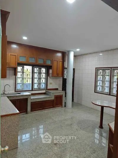 Spacious kitchen with granite countertops and wooden cabinets in a modern home.