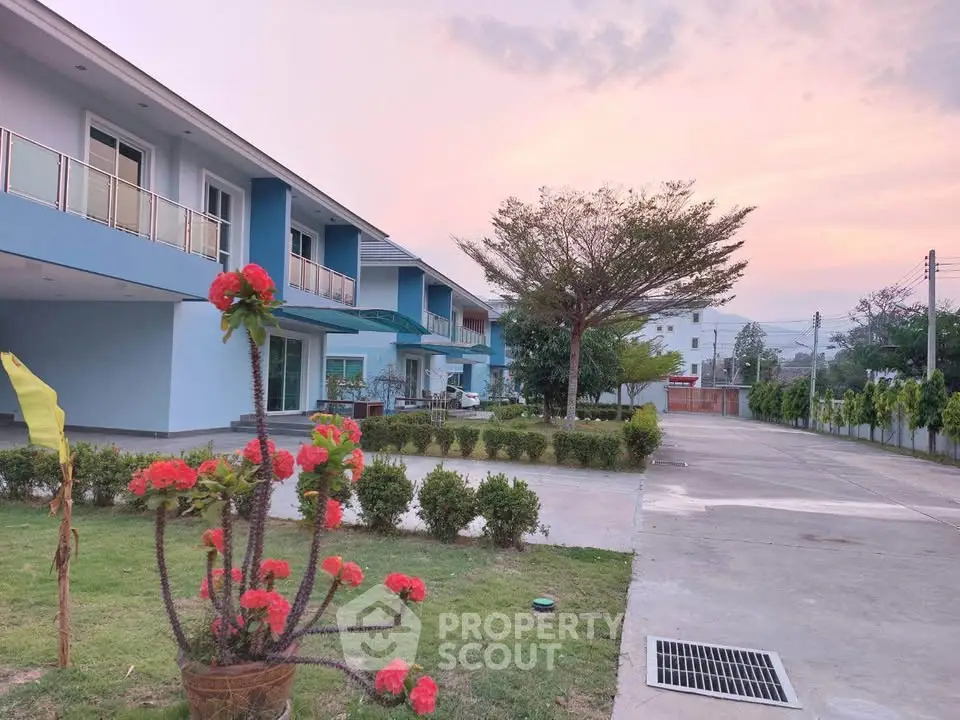 Charming residential building with lush garden and scenic sunset view, perfect for serene living.