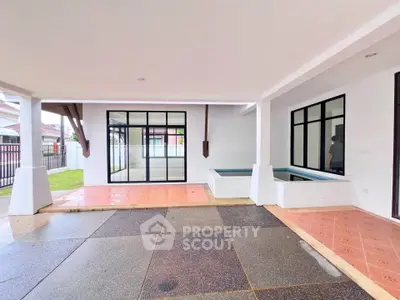 Spacious covered patio with modern design and large windows in a residential property.