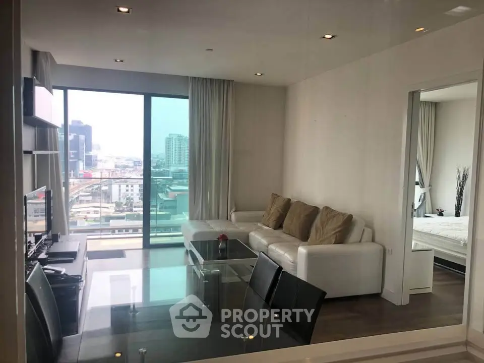 Modern living room with city view, featuring sleek furniture and large windows for natural light.
