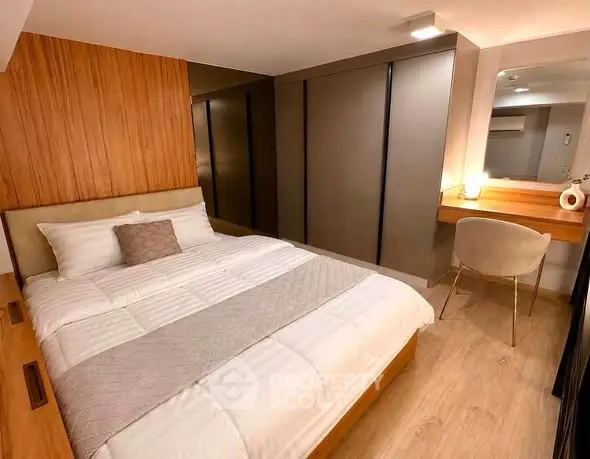 Modern bedroom with stylish wood paneling and cozy lighting, featuring a comfortable bed and sleek workspace.