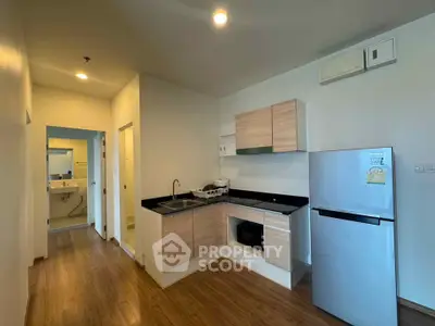 Modern kitchen with sleek cabinetry and stainless steel appliances in a cozy apartment setting.