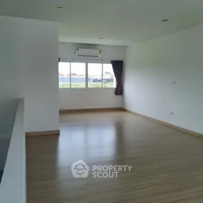 Spacious unfurnished room with large window and wooden flooring, perfect for customization.