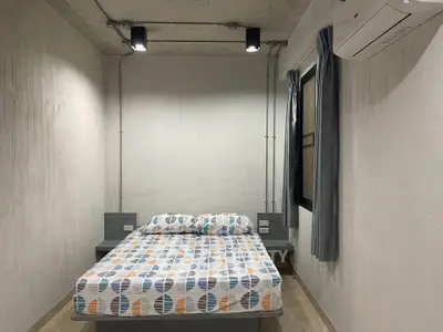 Modern minimalist bedroom with concrete ceiling and air conditioning unit.
