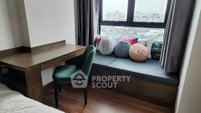 Cozy study nook with city view, featuring a wooden desk and cushioned window seat.